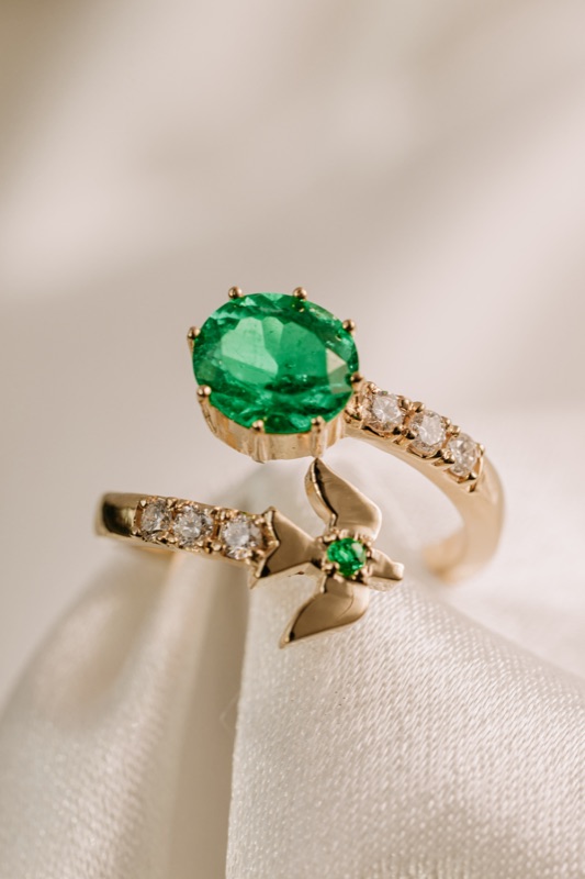 Open ring in 18k gold with oval emerald, diamonds, and bird detail