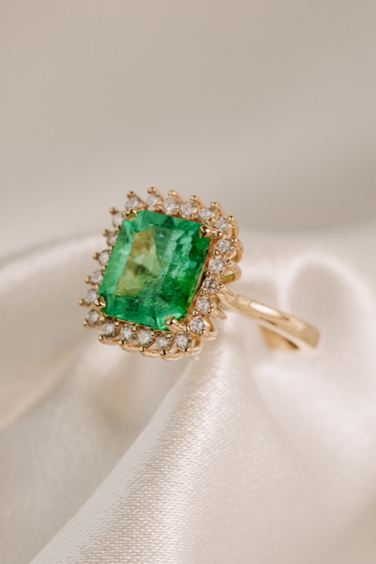 Halo ring in 18k gold with emerald-cut Colombian emerald surrounded by diamonds