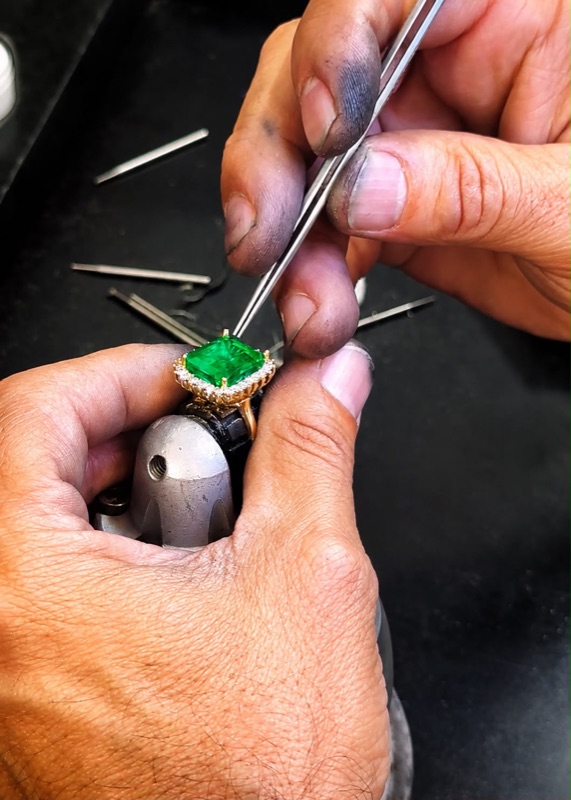 An artisan setting the stone into a ring at the bench