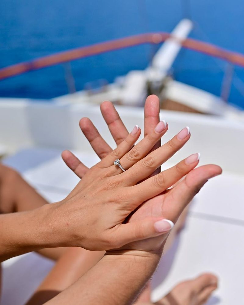Engagement ring worn on a hand against a seaside backdrop