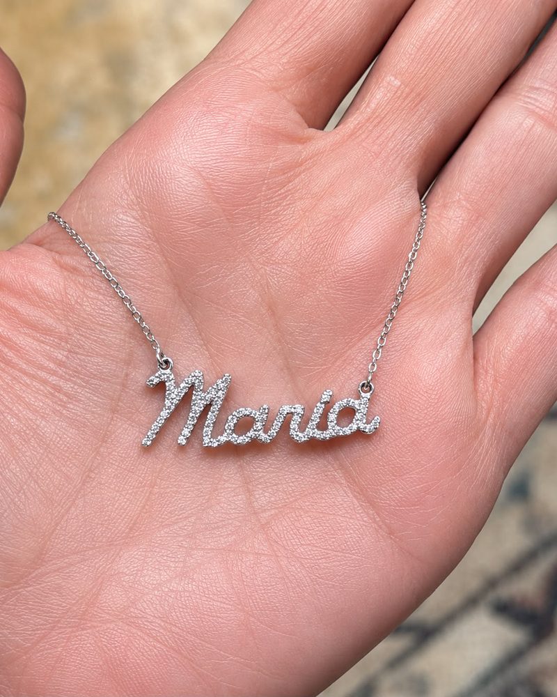 Personalised name necklace in white gold with diamonds, held in a hand