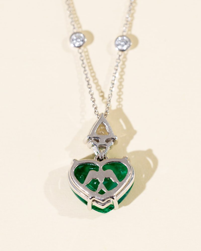 Heart-shaped emerald pendant in white gold on a chain with diamond stations