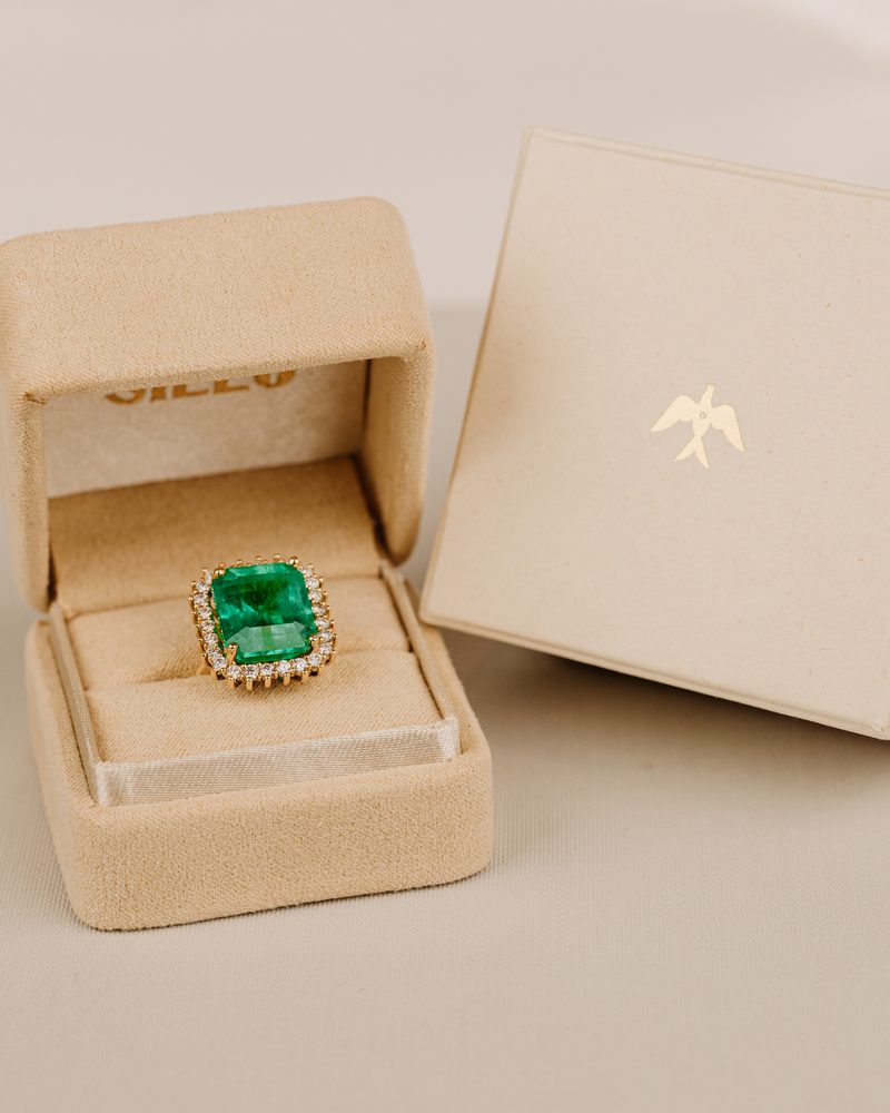 Emerald ring with a diamond halo in 18k gold, in its Sileo box
