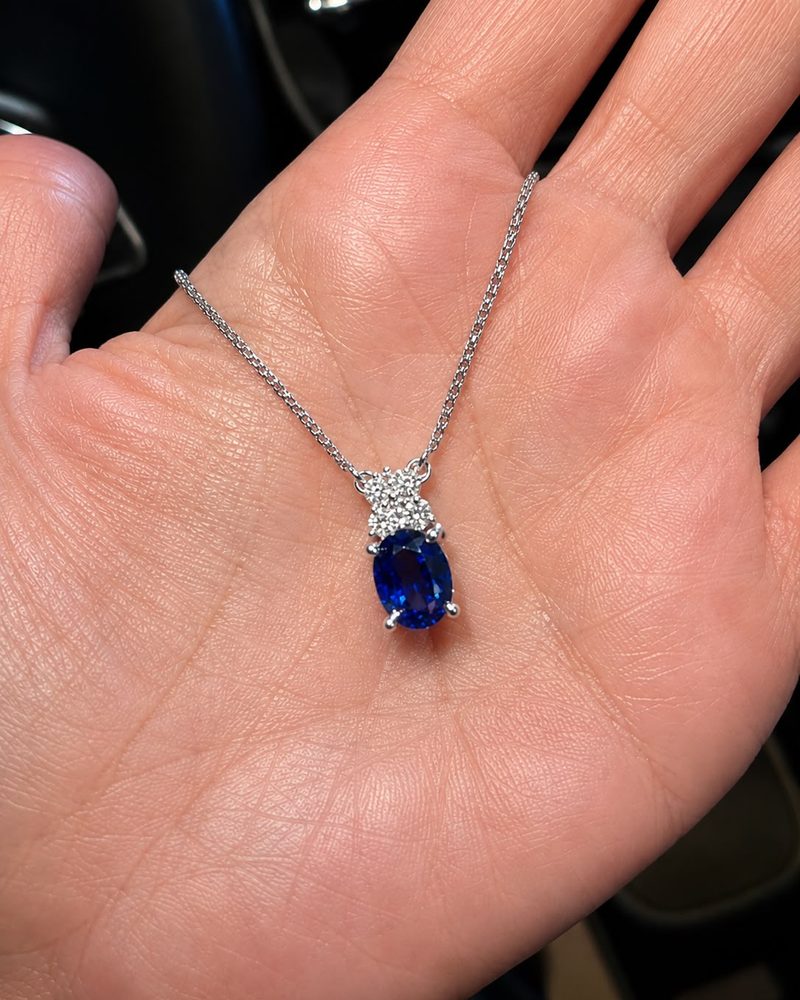 Oval blue sapphire pendant with diamonds on a white gold chain